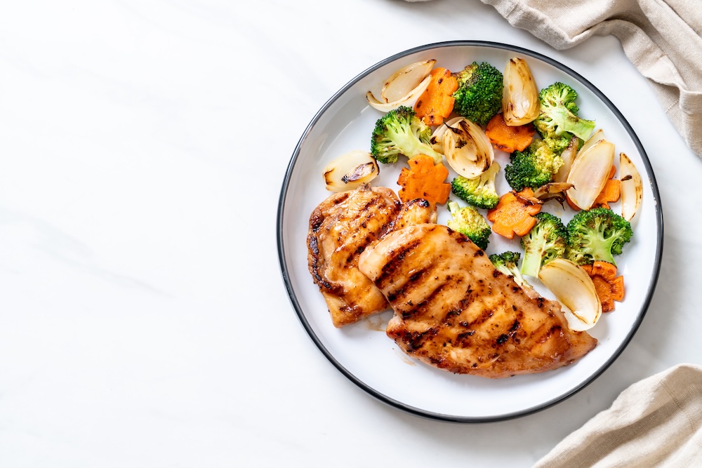 Healthy plate of food with grilled chicken breast and vegetables.