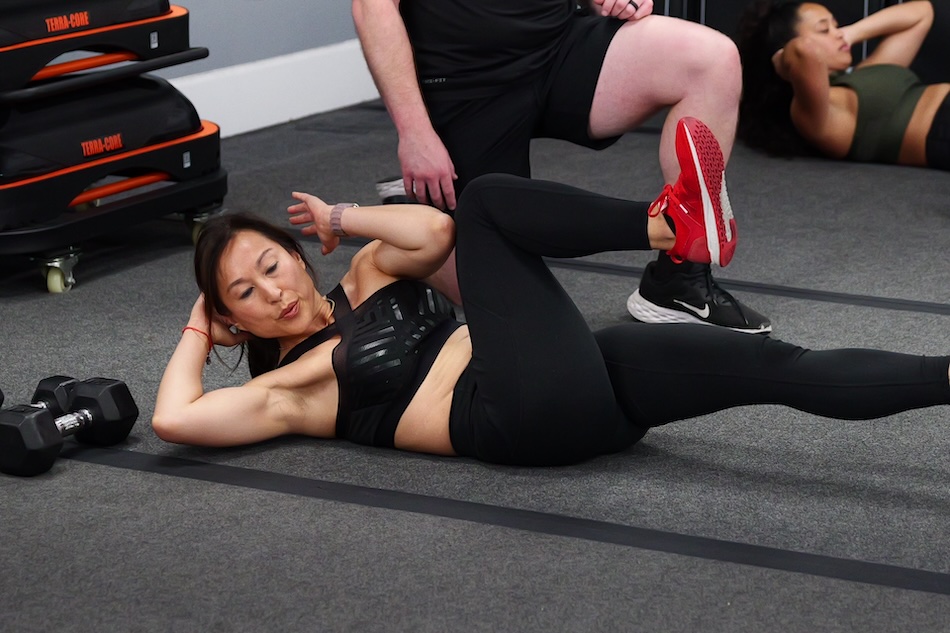 A woman working out core muscles in group workout gym.