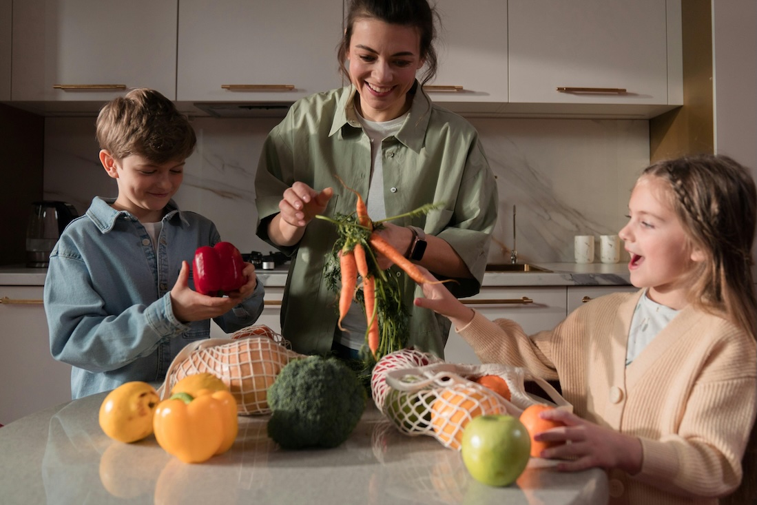 Smiling family with whole fruits and vegetables in the kitchen